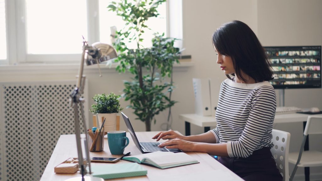 eine Frau, die an einem Schreibtisch sitzt und einen Laptop-Computer benutzt und die Jahresabschlussprüfung macht