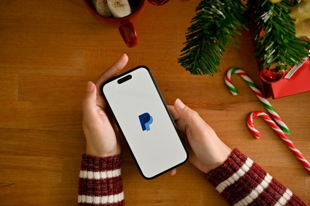 Jemand hält Handy mit PayPal in der Hand 