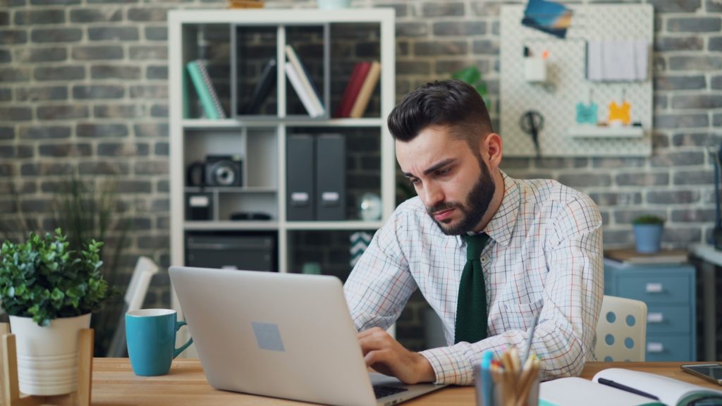 ein Mann, der vor einem Laptop-Computer sitzt