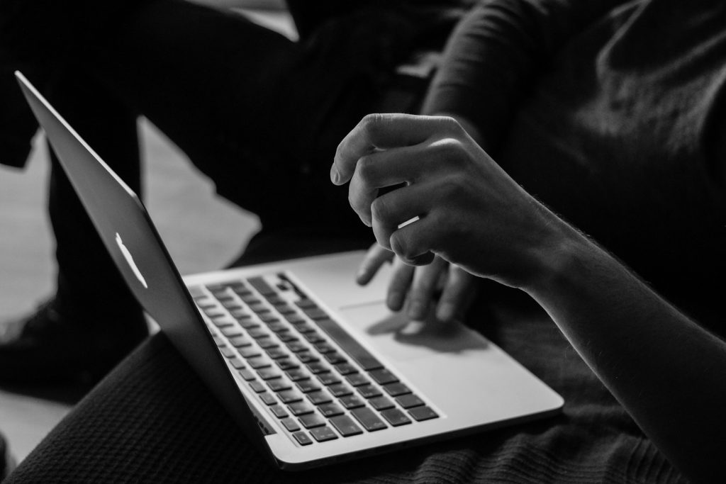 Graustufenfoto einer Person, die ein MacBook benutzt