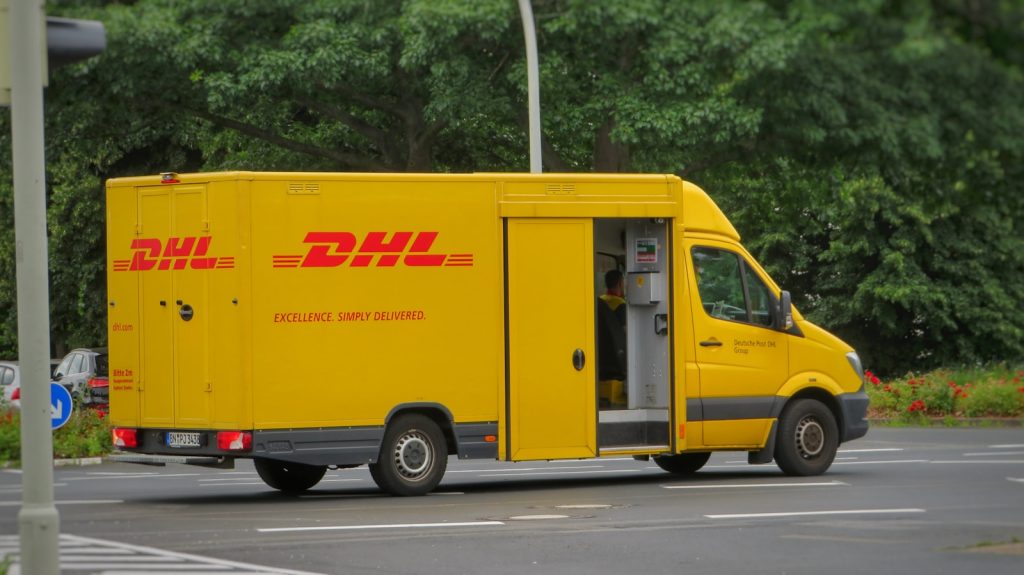 gelber und weißer Lieferwagen auf der Straße bei Tag Pit Paketen von Worldtech Client / Logistics 