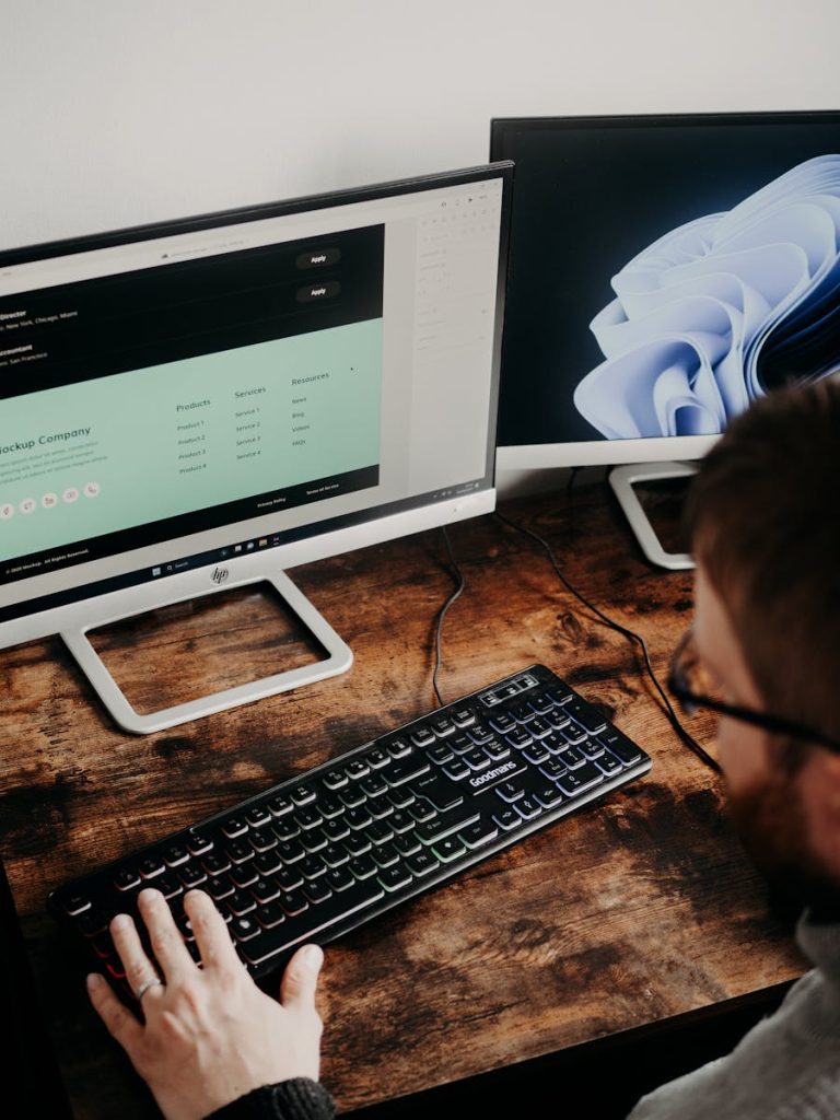 Erwachsener Mann nutzt zwei Monitore für Webdesign in einer Heimbüroumgebung.