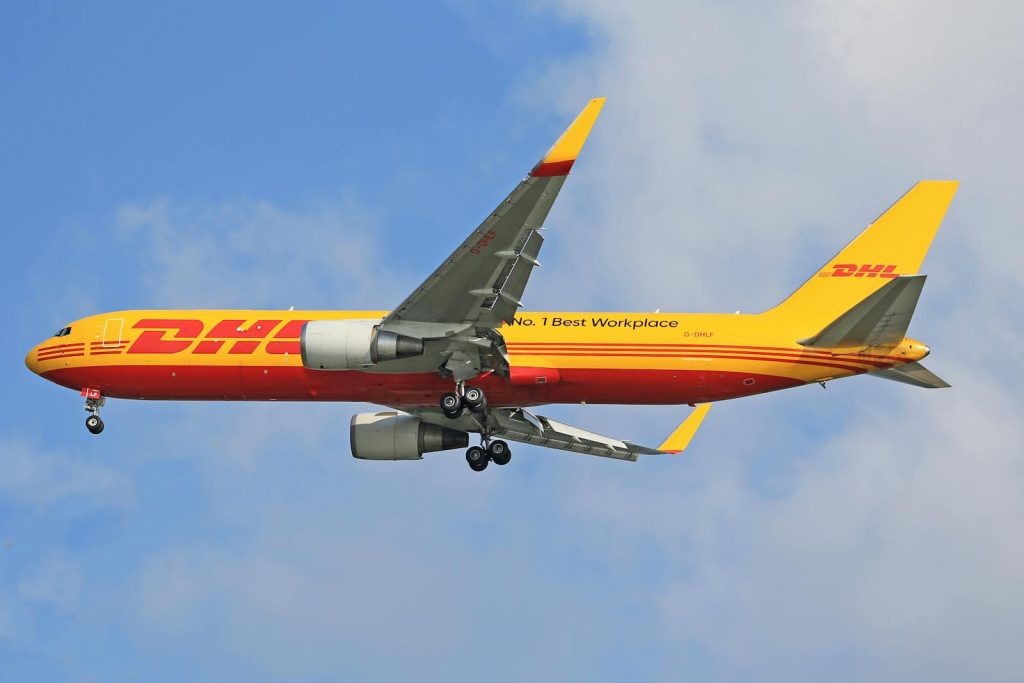 Ein DHL-Frachtflugzeug fliegt hoch am klaren blauen Himmel und demonstriert Transporteffizienz.
