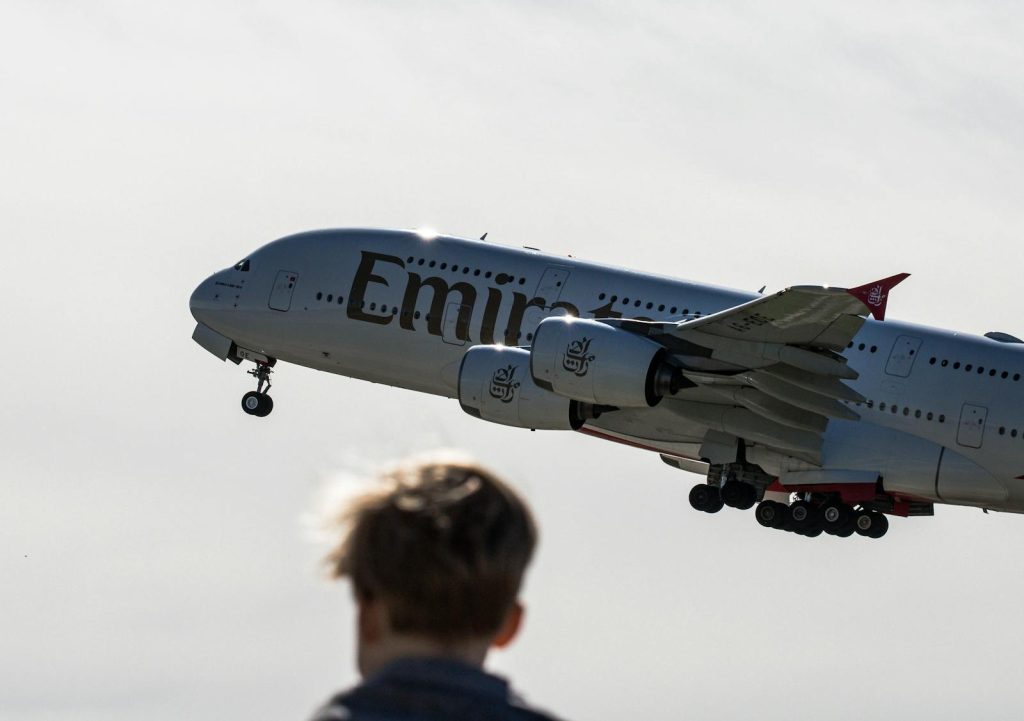 Ein atemberaubendes Bild, das einen Emirates Airbus A380 beim Start am Flughafen Zürich zeigt, während ein Zuschauer zuschaut.