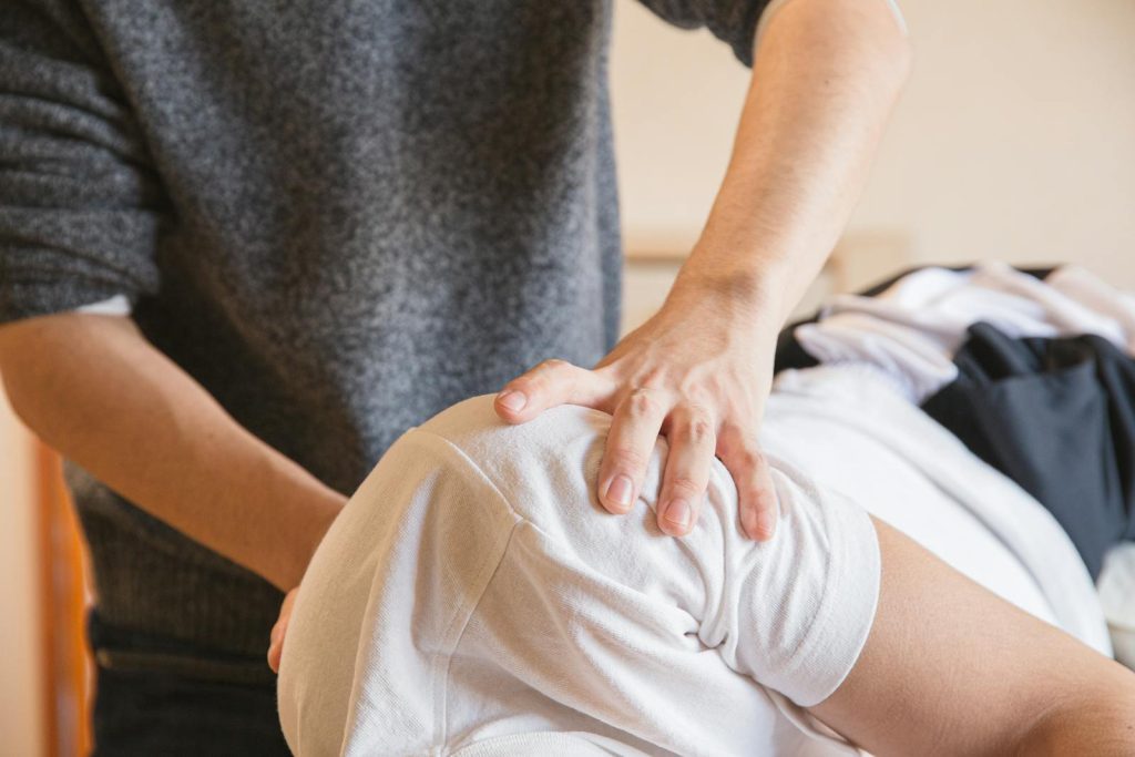 Nahaufnahme eines Chiropraktikers, der drinnen eine Schultertherapie an einem Patienten durchführt.