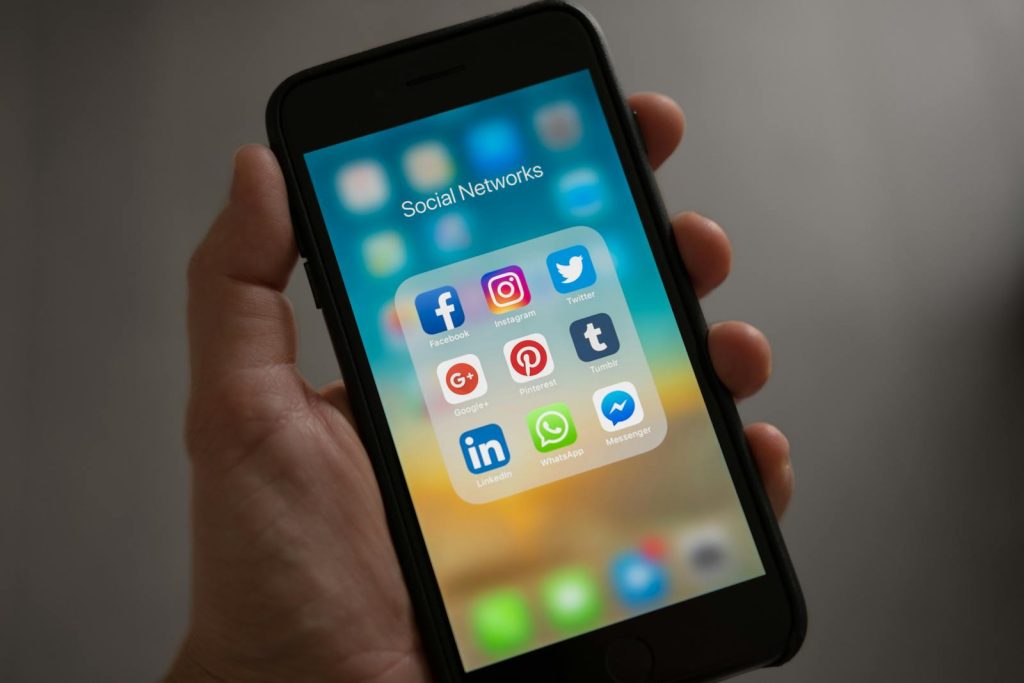 Ein Smartphone mit verschiedenen Social-Media-Symbolen in der Hand, das moderne Kommunikations-Apps präsentiert.