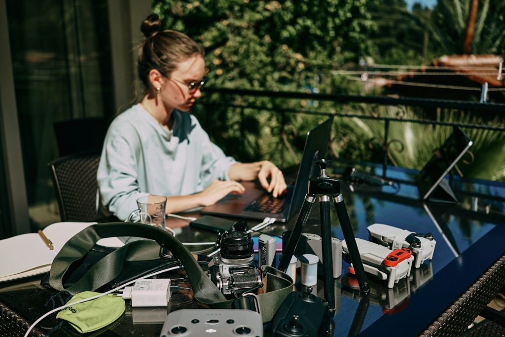 Frau mit Laptop und anderen elektrischen Geräten an einer Powerstation